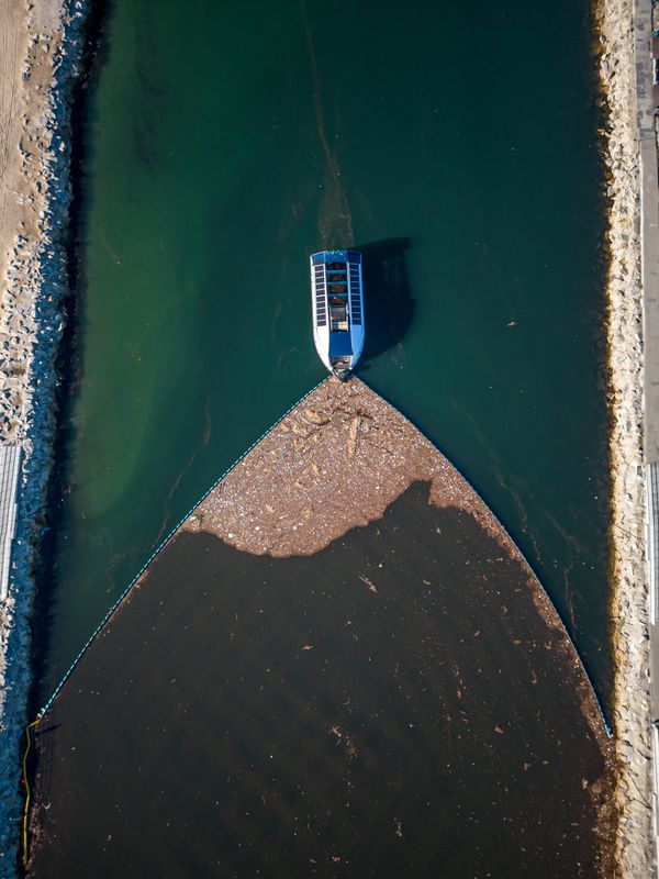 Aerial view of an Interceptor river cleanup system collecting plastic with a containment boom
