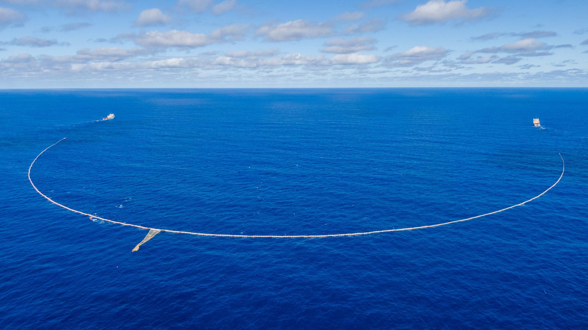 System 03 - The Ocean Cleanup's floating barrier deployed in the Great Pacific Garbage Patch, with support tender vessel visible
